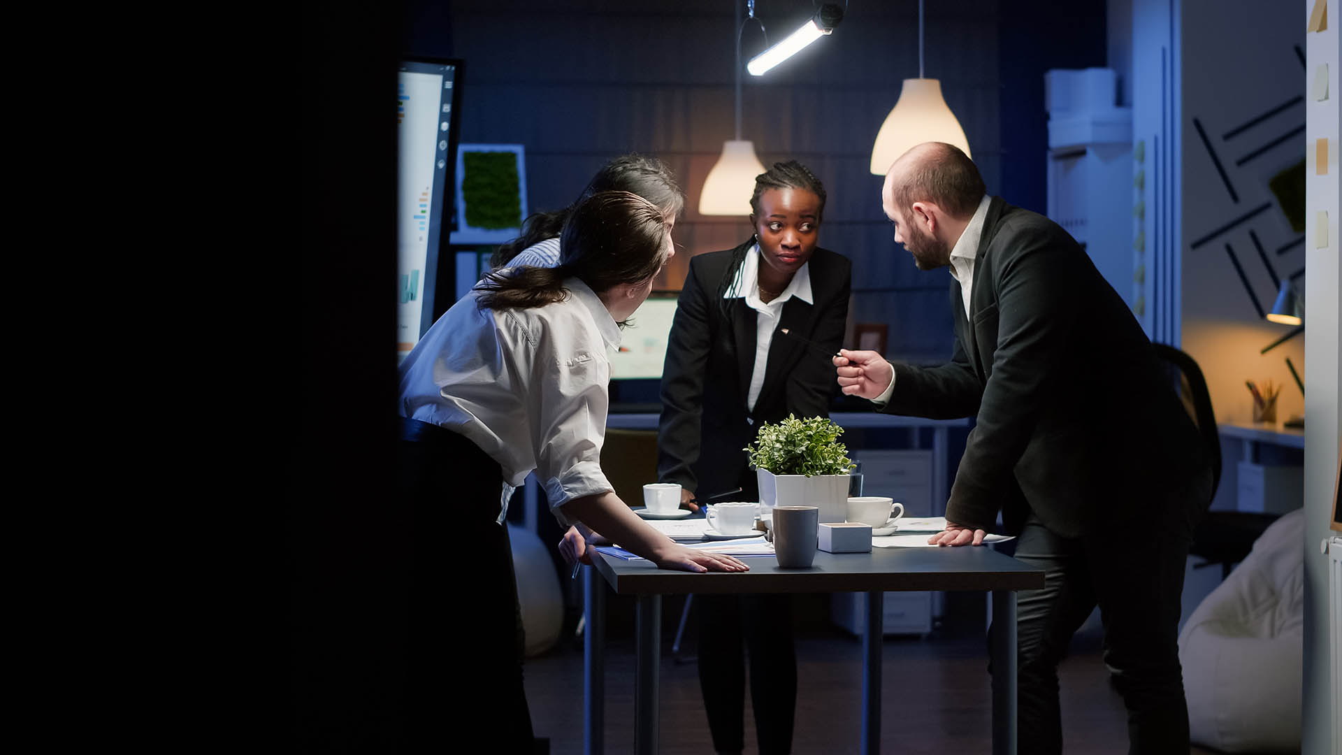 Diverse businesspeople discussing over management paperwork standing at conference table